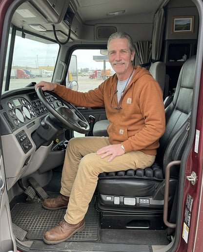 Trucker sitting on the Celinva travel cushion in his truck cab